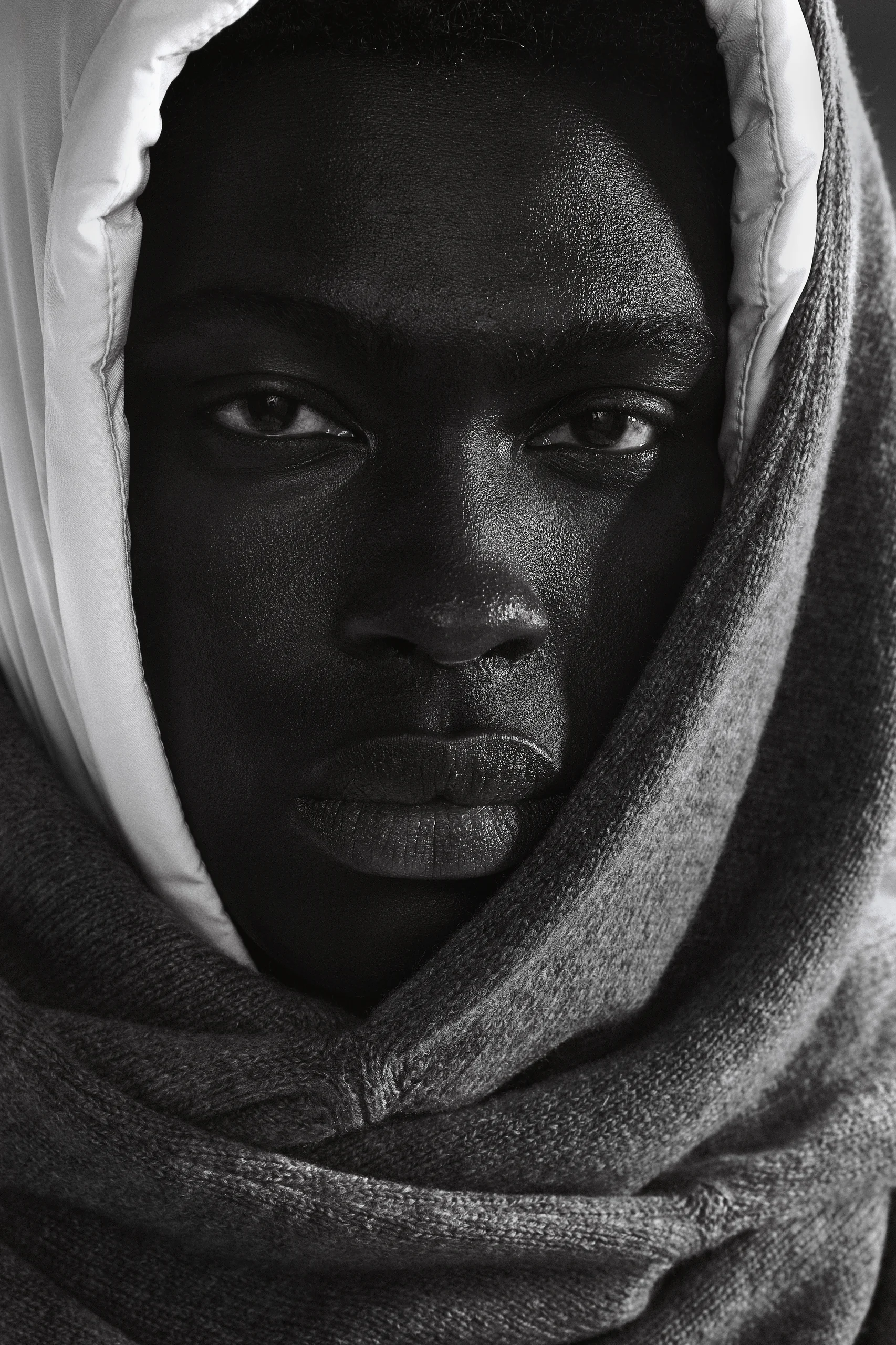 Close-up van een model met witte capuchon en grijze gebreide sjaal, Gogetti editorial in zwart-wit